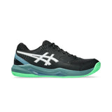 Black athletic shoe with green sole on a white background