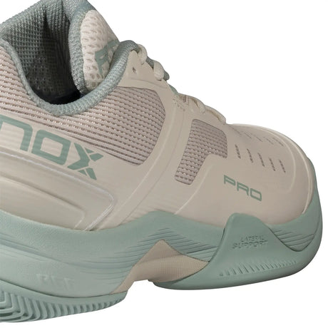 Beige and green athletic shoe with 'On' branding on a white background