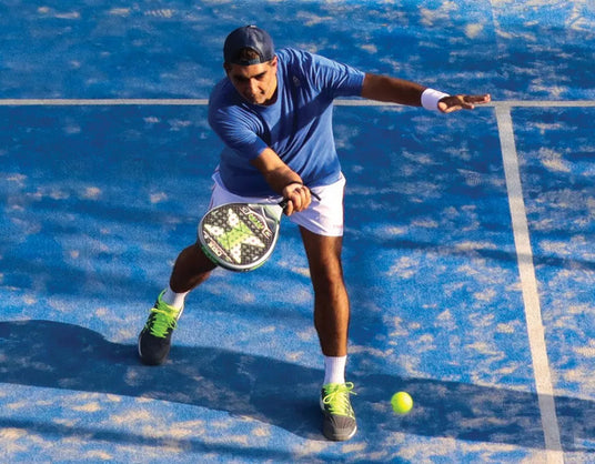 Person playing paddle ball on a blue court